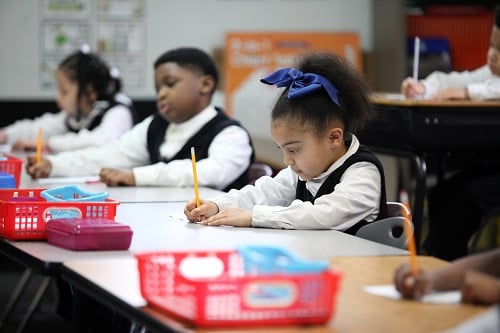 Children in a classroom writing at their desks.