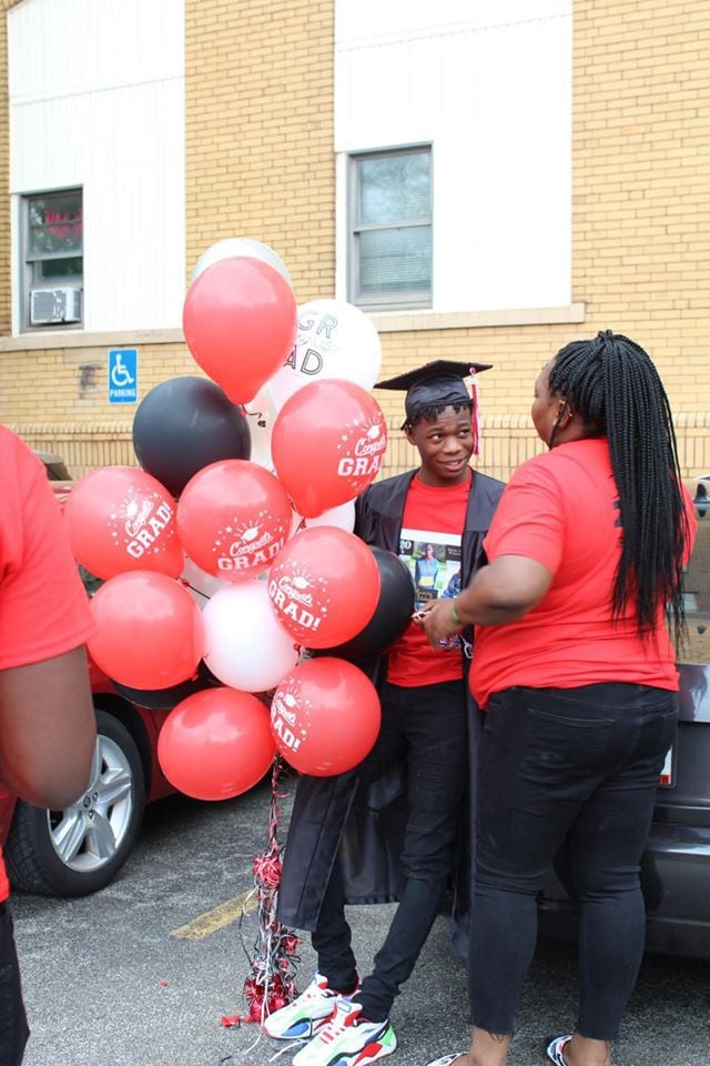 Adult in graduation cap and gown with balloons.